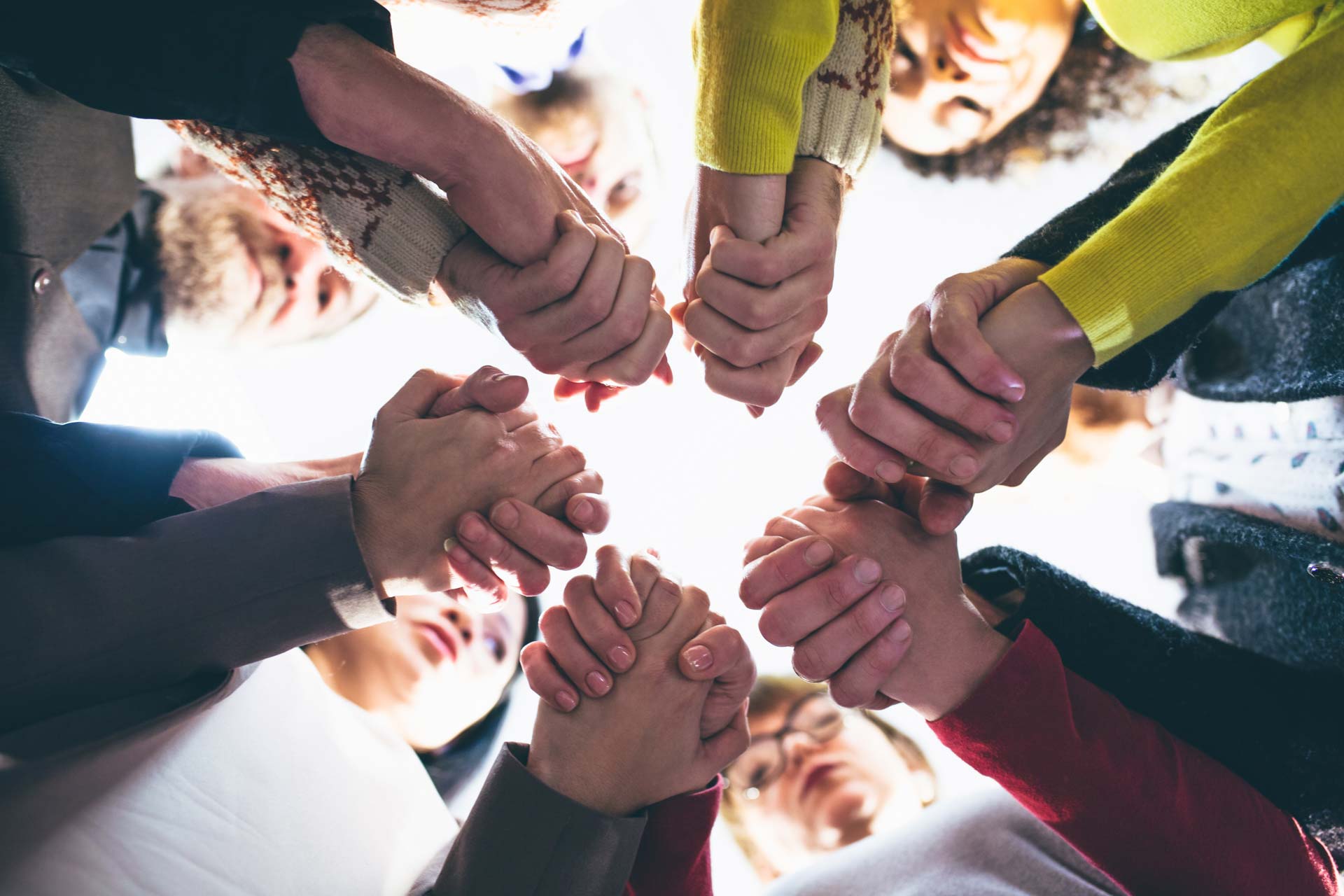 a group of people joining hands in a circle during a support session