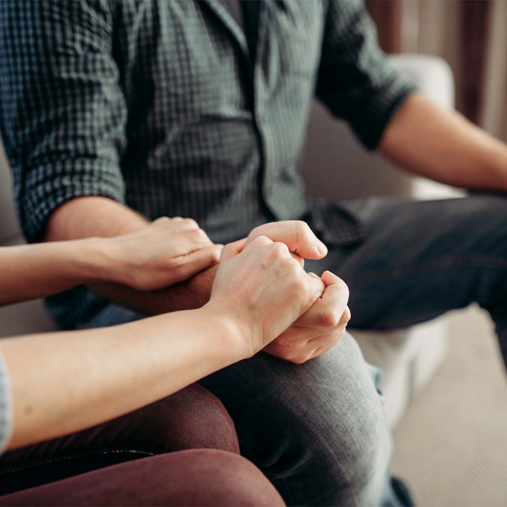 two people sitting together, one offering support to the other