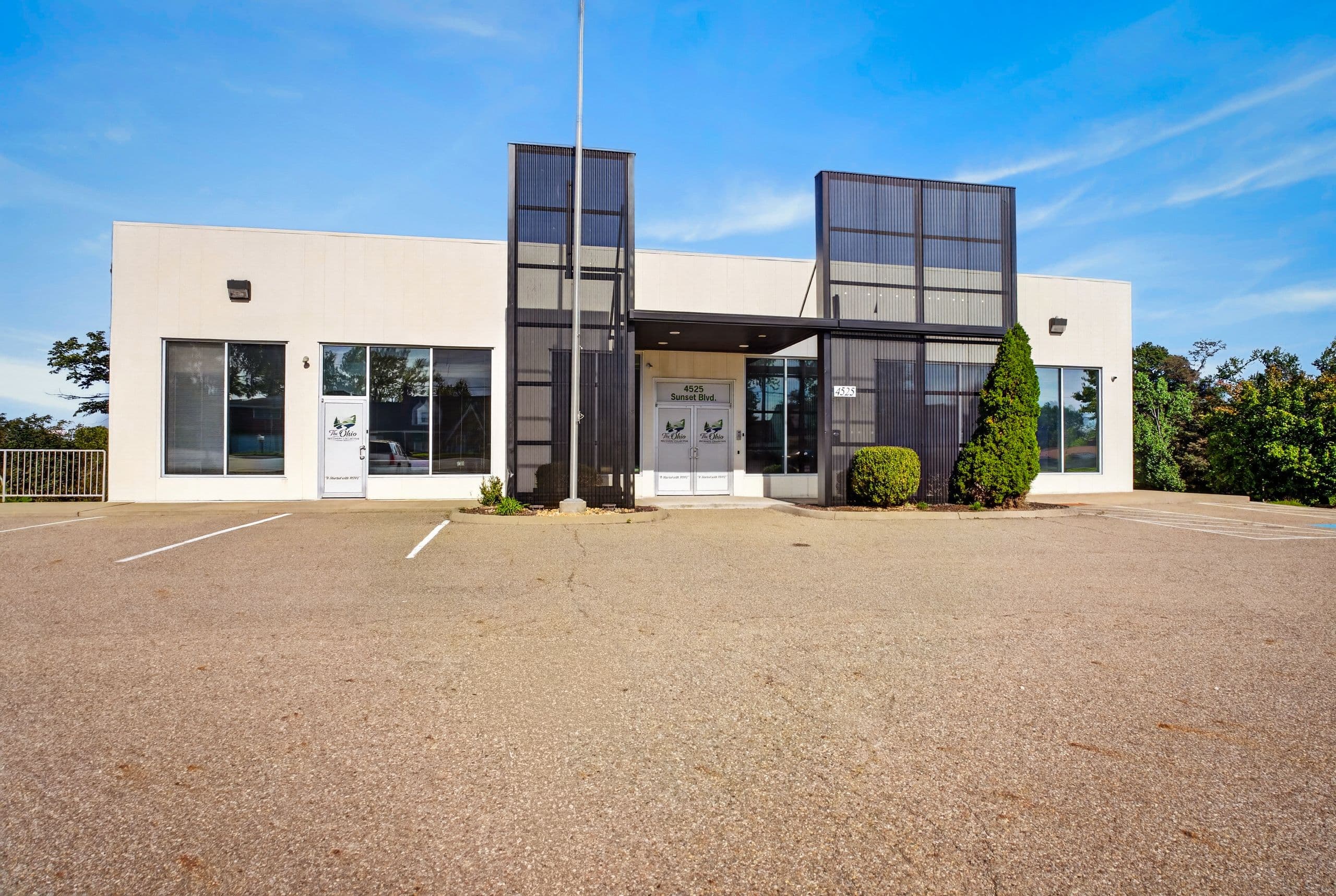 The front of the clinic, a white single-storey building with dark glass towers at the entrance