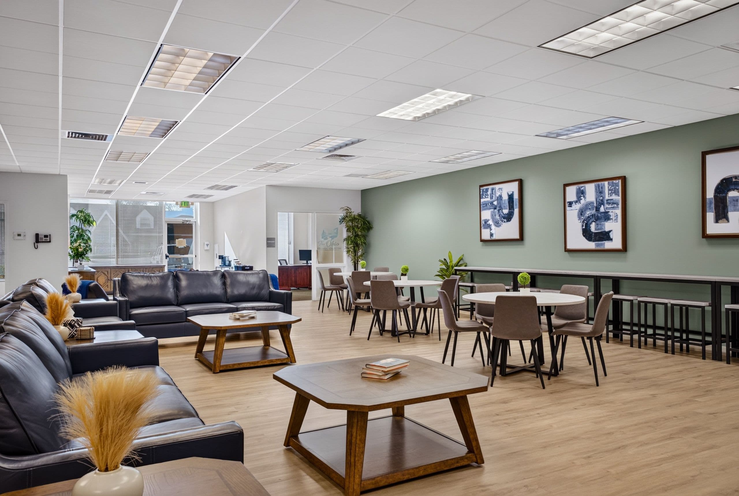 Leather sofas around a coffee table in the lounge, with dining tables beyond